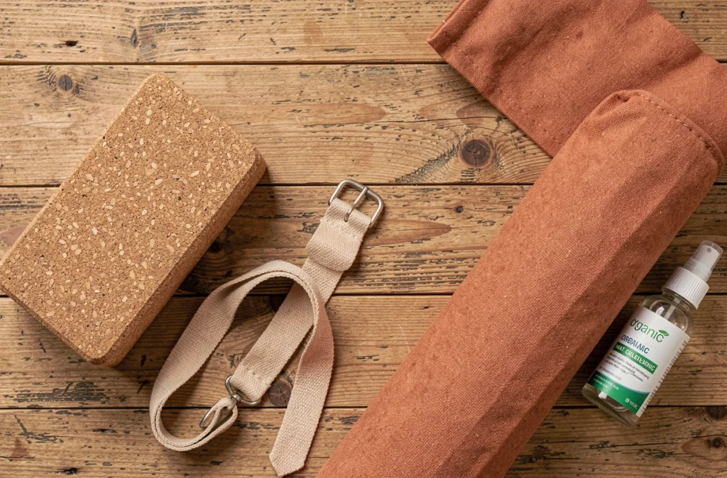 Vue de dessus d'accessoires de yoga durables en liège, coton naturel et verre sur surface en bois recyclé